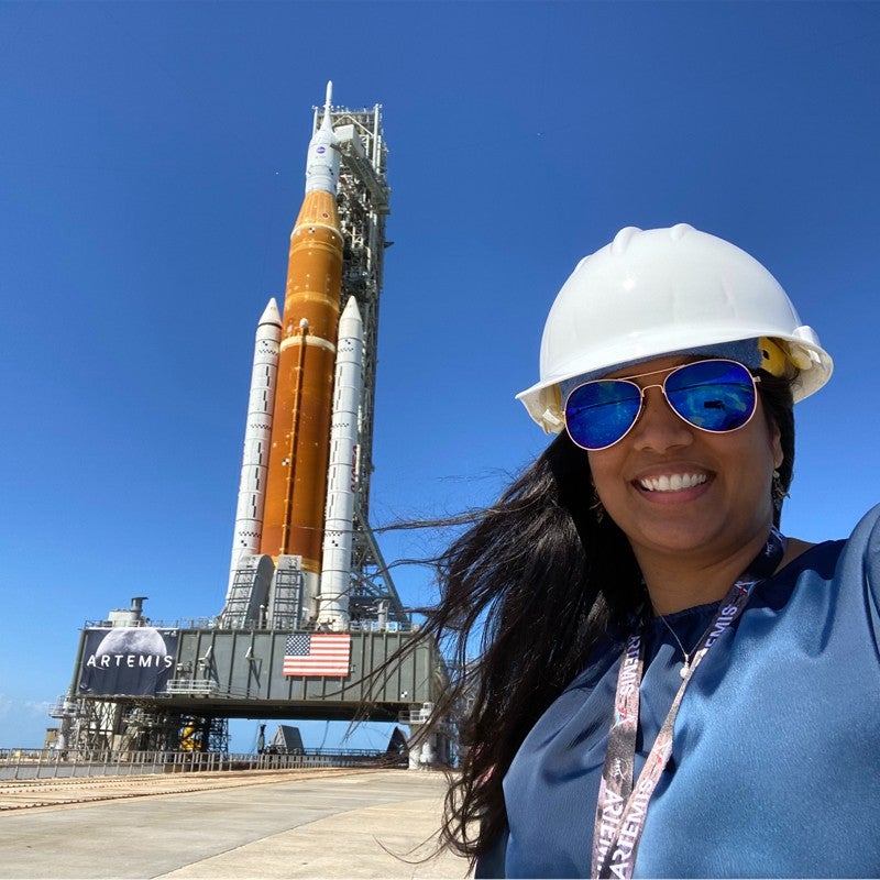 Laura Poliah in front of the Space Launch System rocket