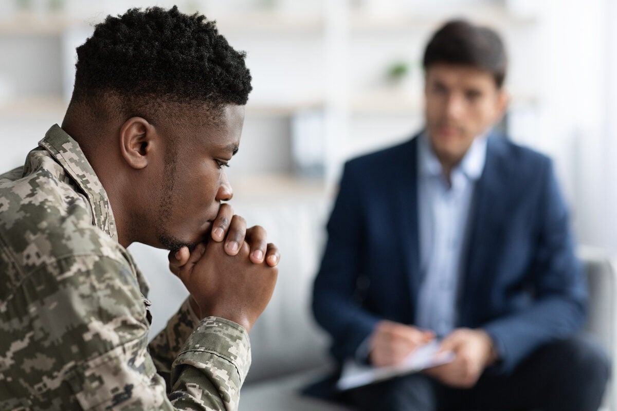 Pensive man in camouflage uniform soldier having conversation with social worker.