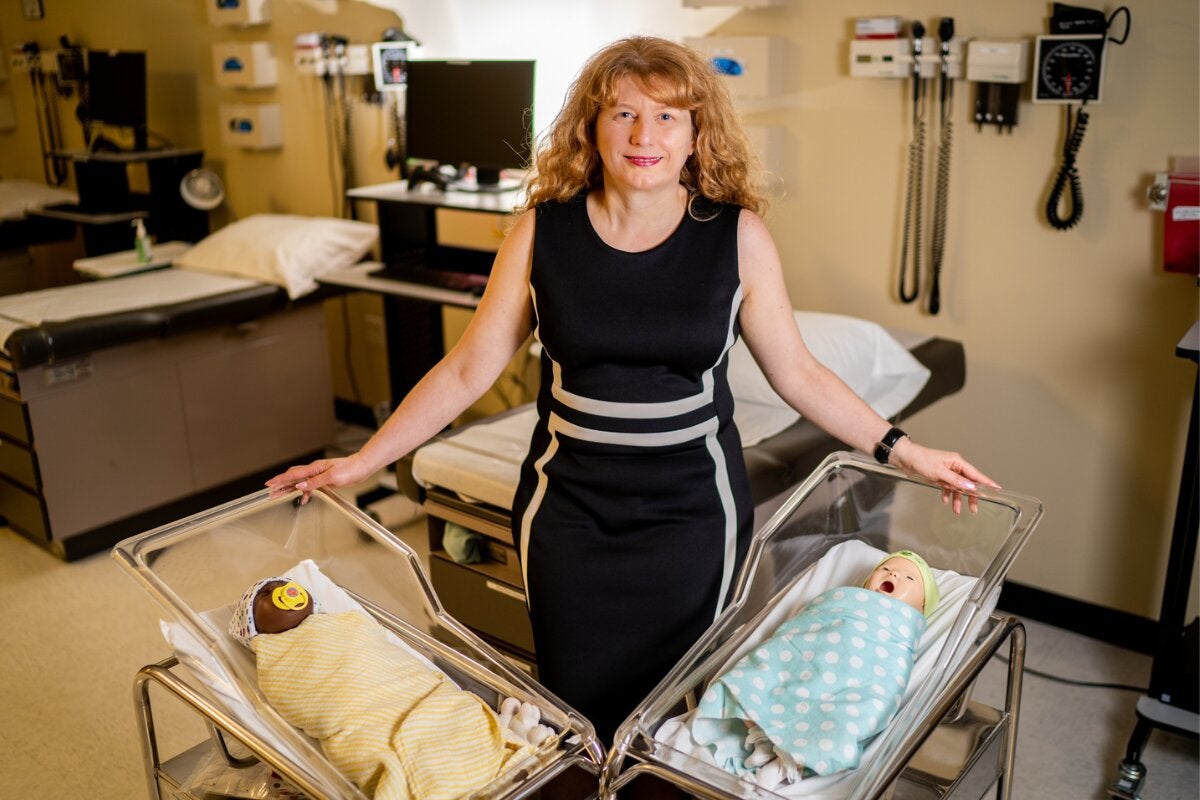 Carmen Giurgescu stands next to two manikin babies
