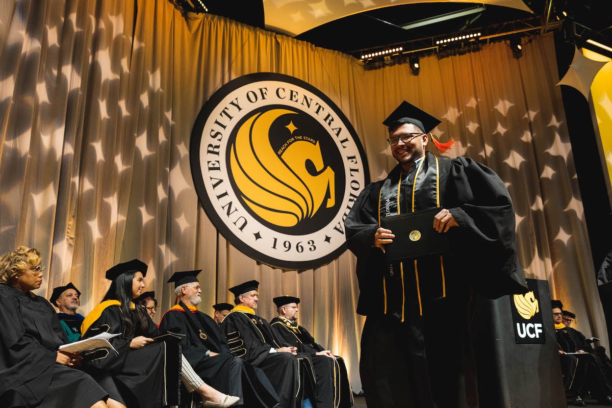 A male graduate crosses a commencement stage