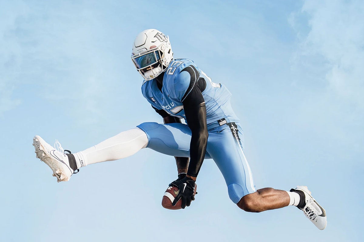 A football player jumping while holding a football