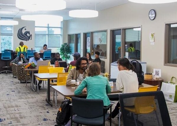 Graduate Student Center multi use room with several students conversing.