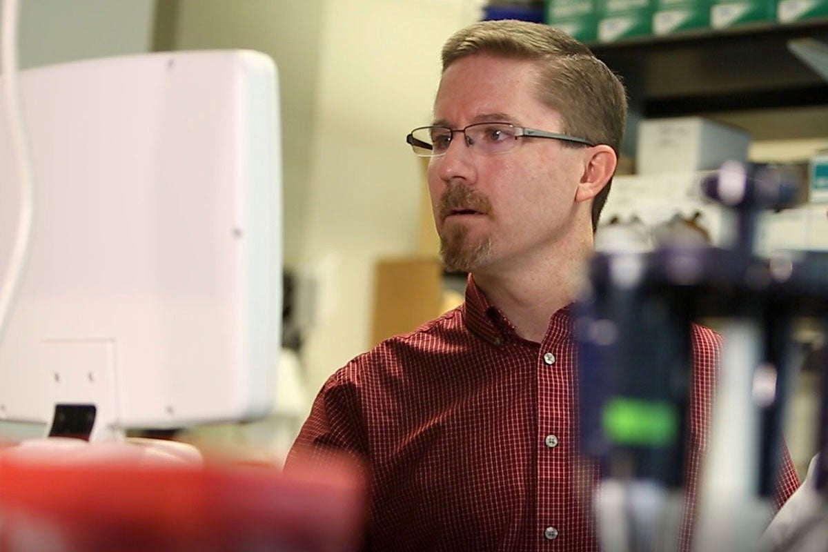 Kyle Rohde analyzing data at a computer in a lab