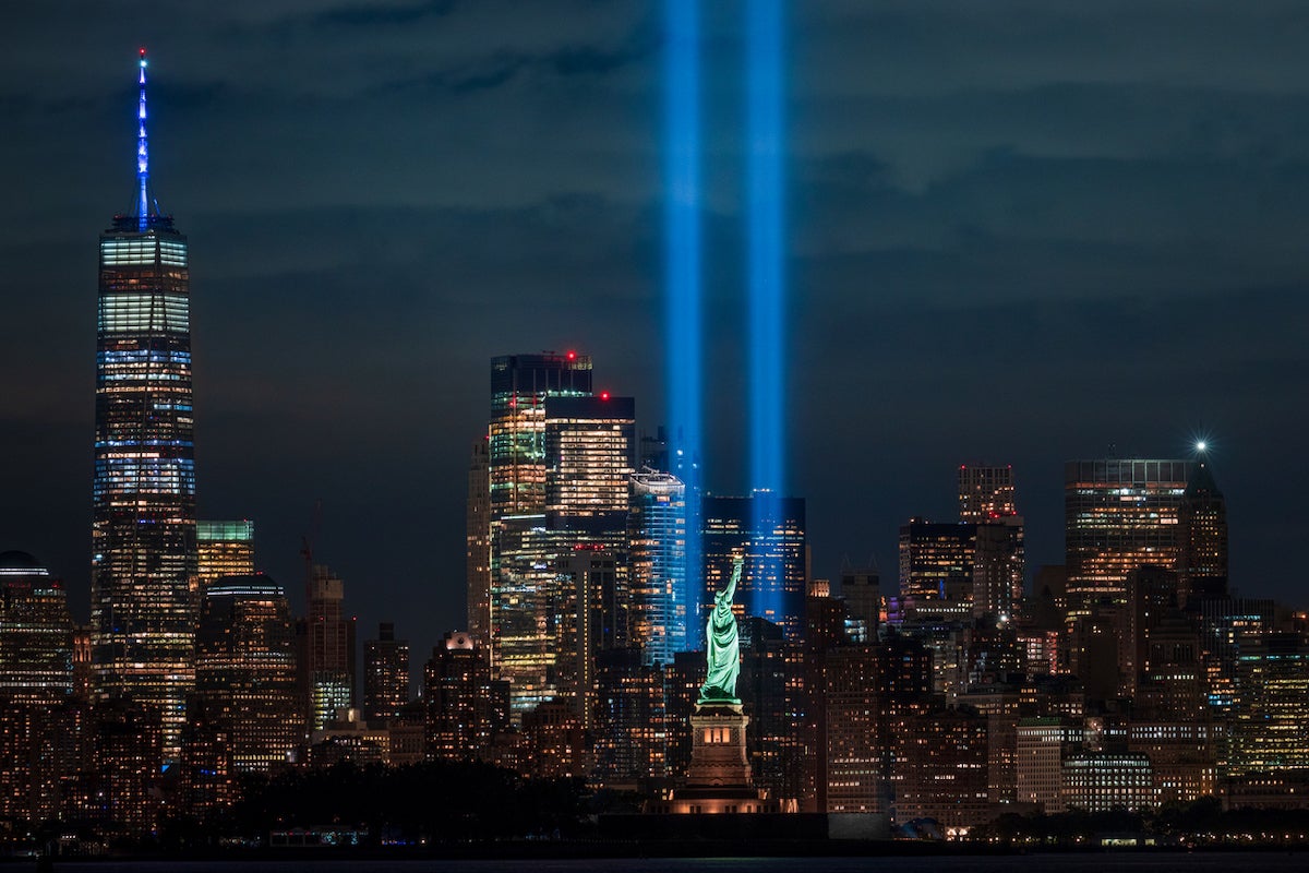 The Tribute in Light 9/11 memorial with the Statue of Liberty. New York City, USA