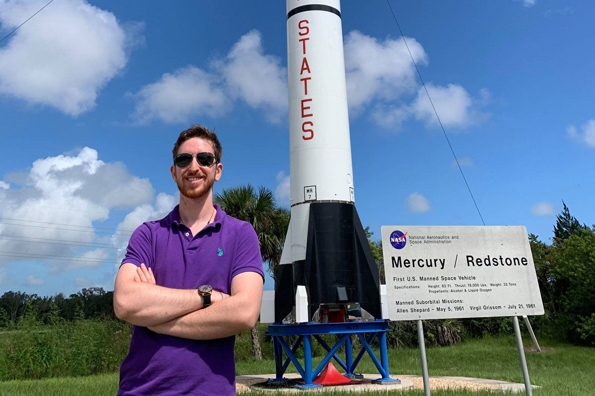 Brandon Kutchera standing in front of a NASA rocket.