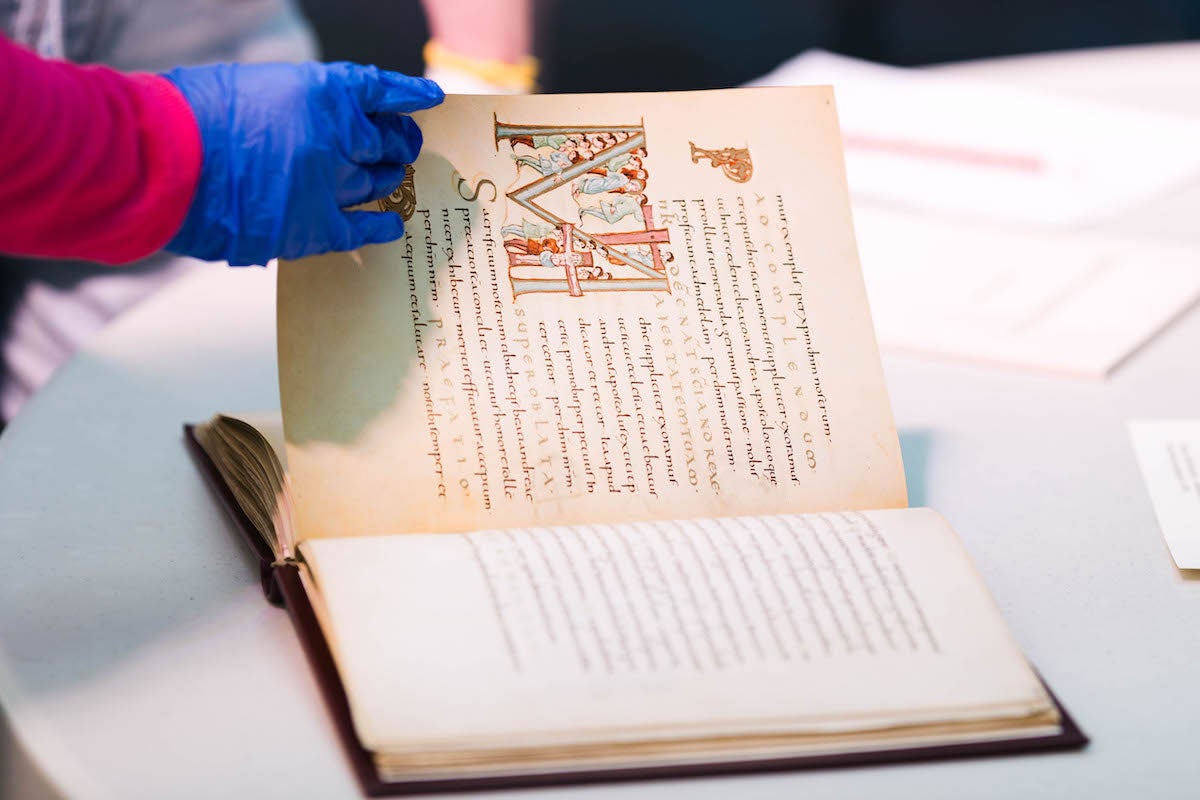 A hand turning a page of a manuscript.