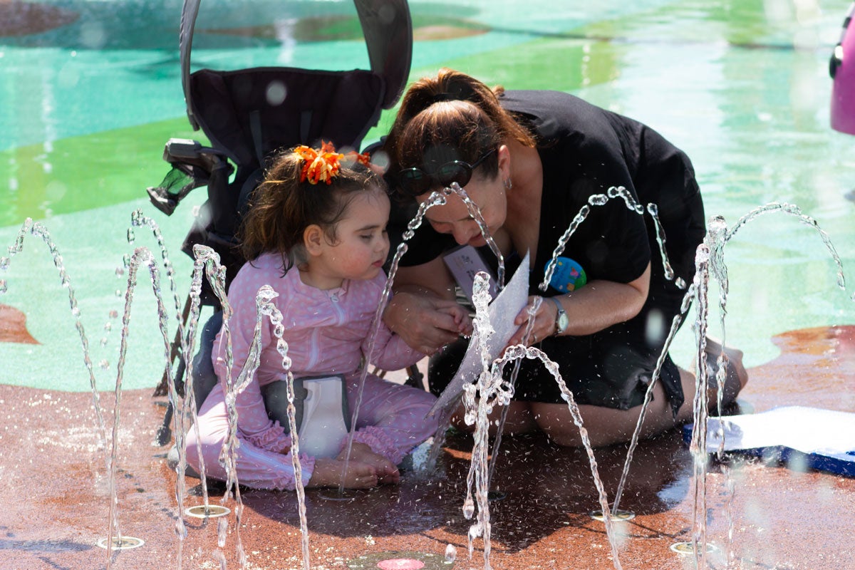 Assistant Professor Julie Feuerstein uses visual aids to communicate with a child enjoying the splash pad at Peppa Pig Theme Park.