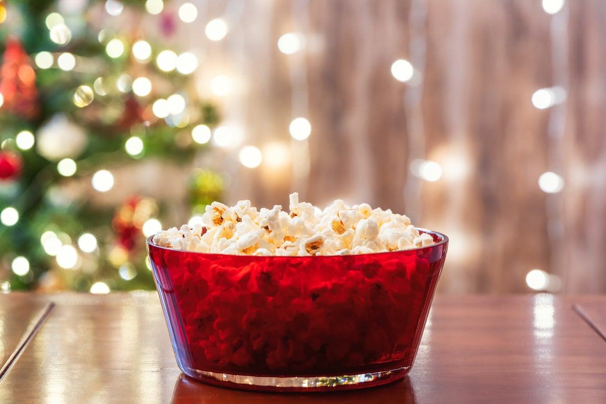 Christmas eve. Red bowl with popcorn on the table near christmas tree. Home cinema. Cropped, close up