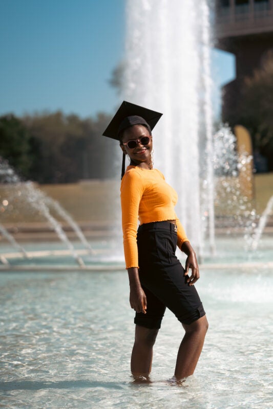 Njeri Kinuthia wears a grad cap while standing in the Reflecting Pond
