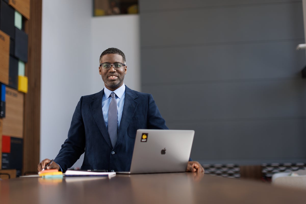 A man wearing a suit stand by a laptop with a stick that says UCF