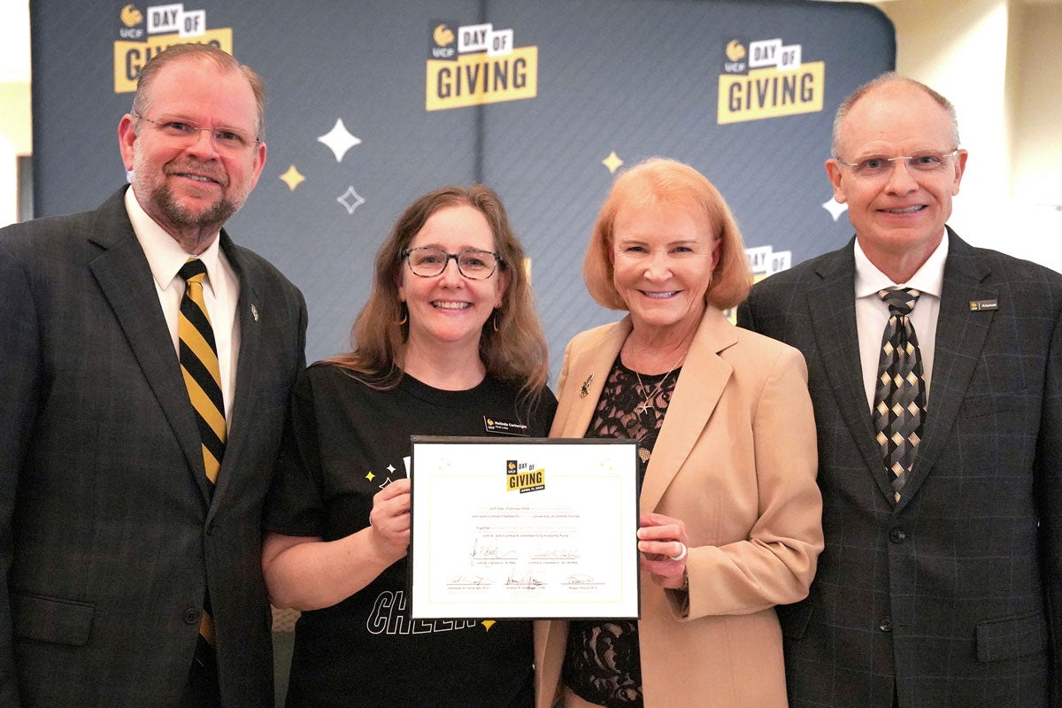 UCF President Alexander N. Cartwright, First Lady Melinda Cartwright, Cynthia Chamberlin ’95 ’98MBA and John Chamberlin ’91MBA pose for a photo will holding a signed piece of paper