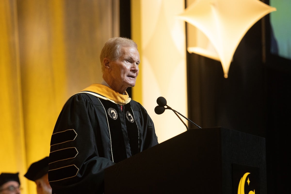 NASA Administrator Bill Nelson wearing a commencement regalia while speaking at a podium