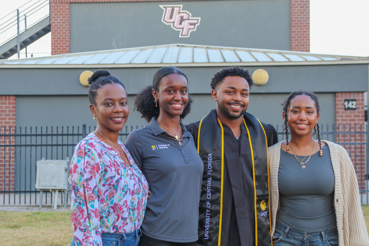 Stephen Frederick, Sulah Monize, David Frederick, Linah Monize and Samuel Frederick pose for a photo with the UCF logo in the background