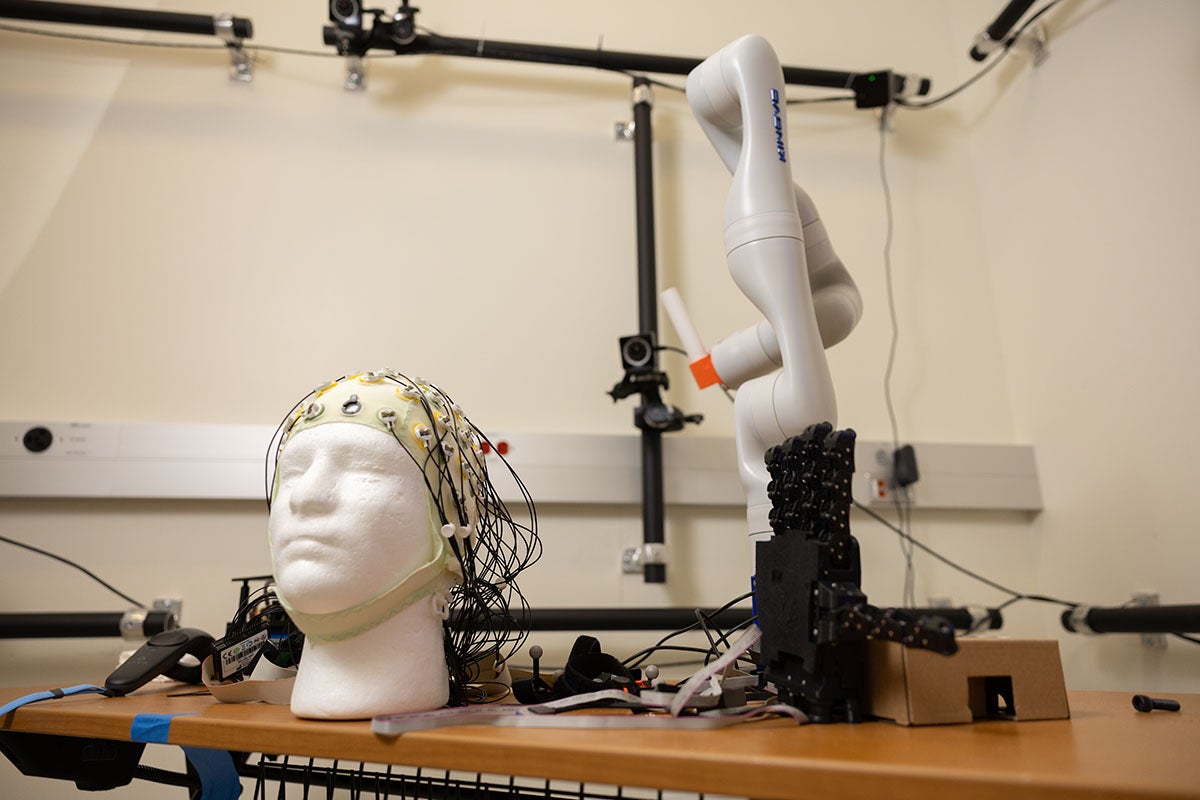 Photo shows a robotic arm and a cap used to track and monitor brain activity for usage in Qiushi Fu's bimanual coordination research.
