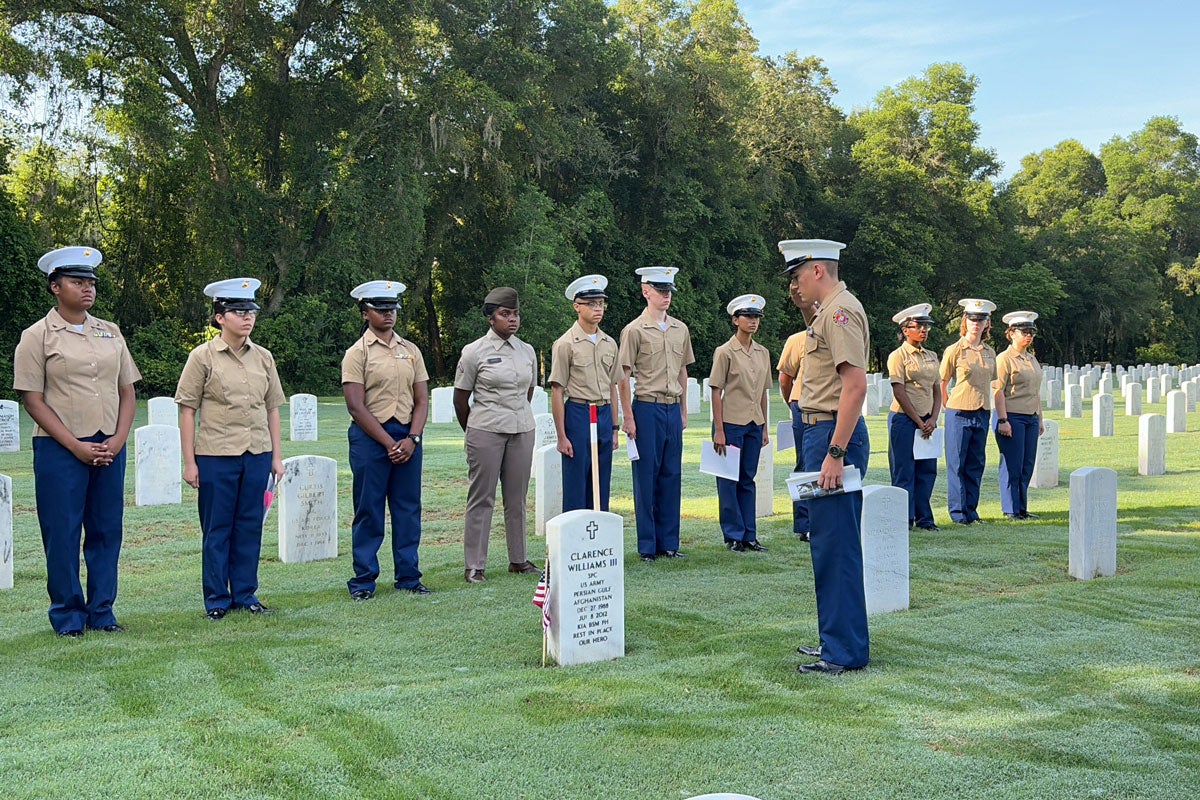 U.S. military service people in uniform standing in a cemetery