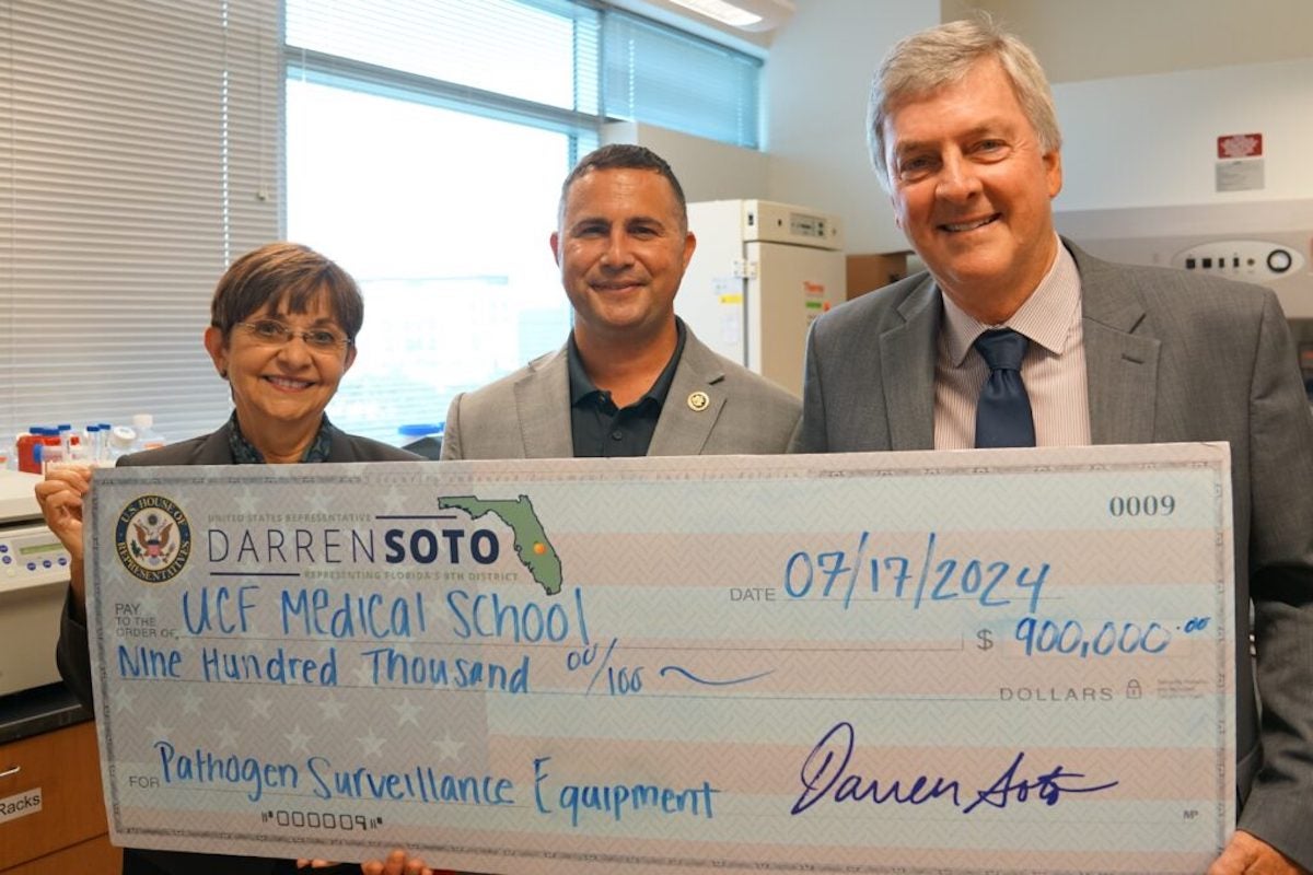 Congressman Darren Soto presents a check to Dean Deborah German and Dr. Griffith Parks.
