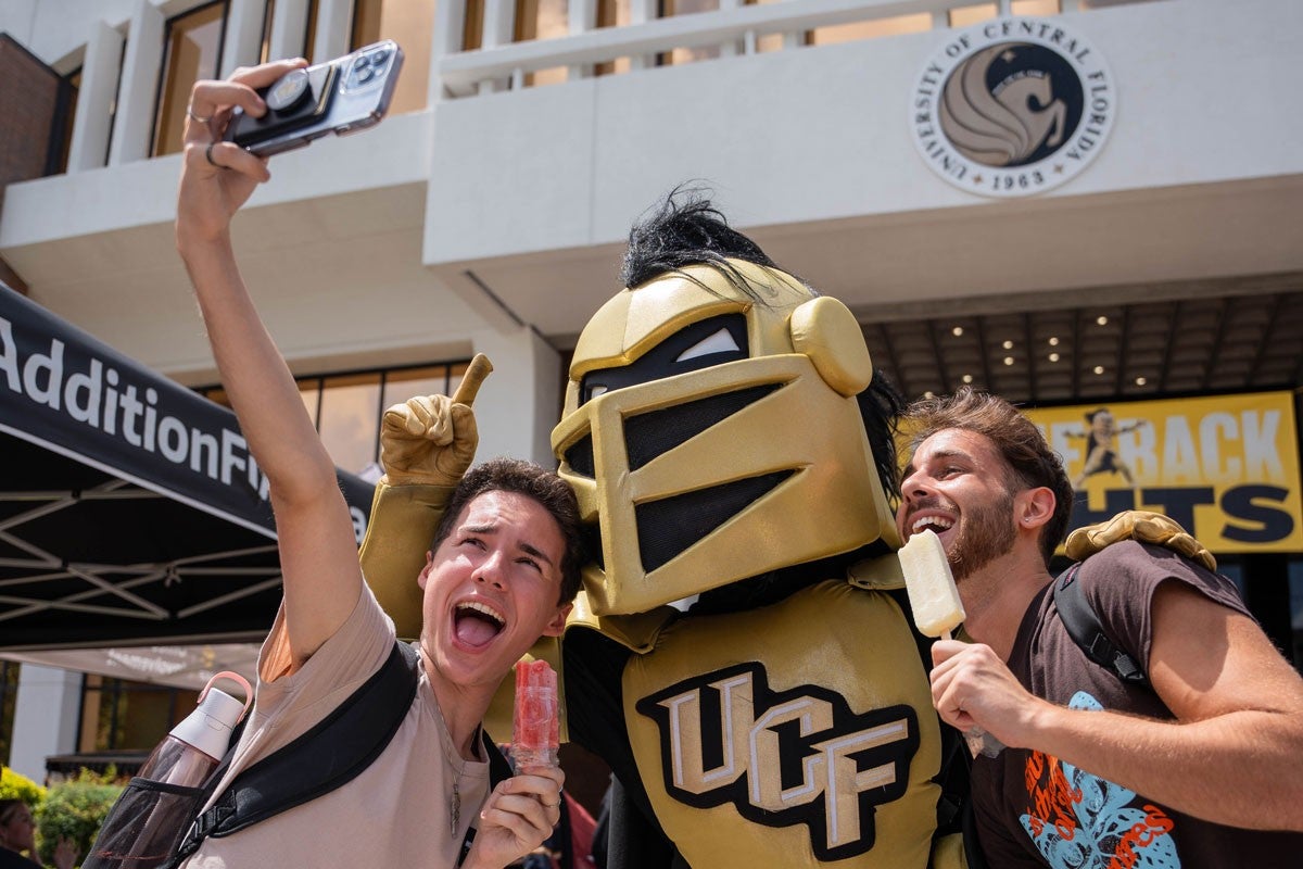 Knightro taking a selfie with two students.