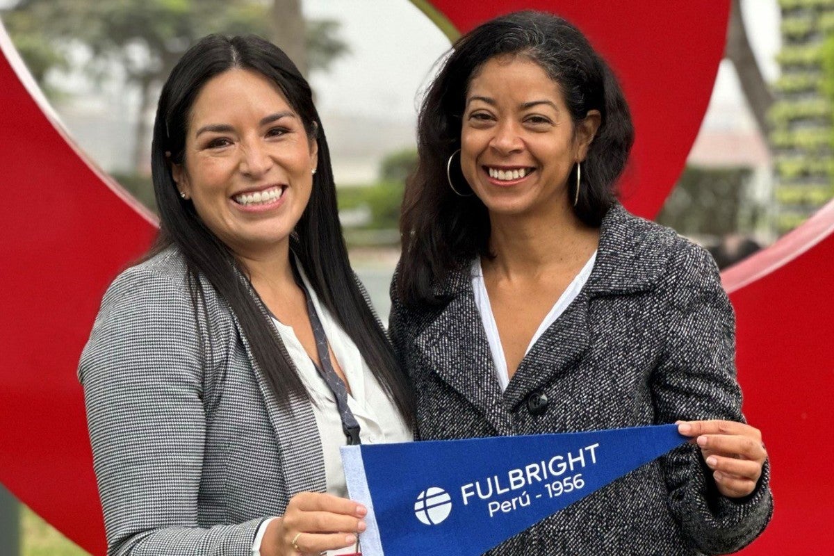 Two women hold up a blue penant flag