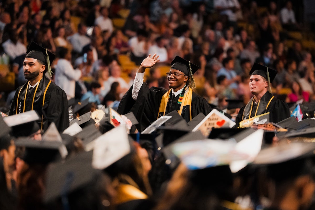 Graduates stand up amongst crowd during UCF's summer 2024 commencement ceremony at Addition Financial Arena