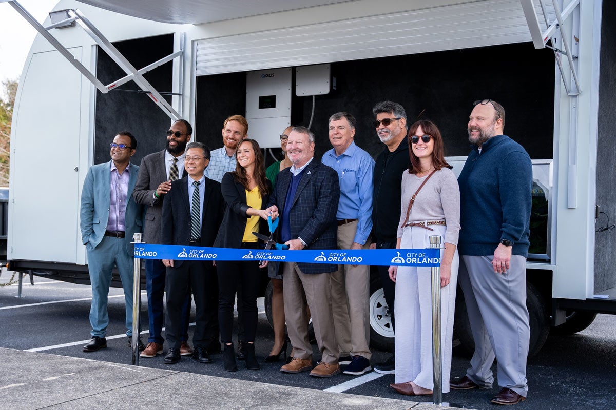 A group of people posing for a photo in front of the REACH Hub trailer