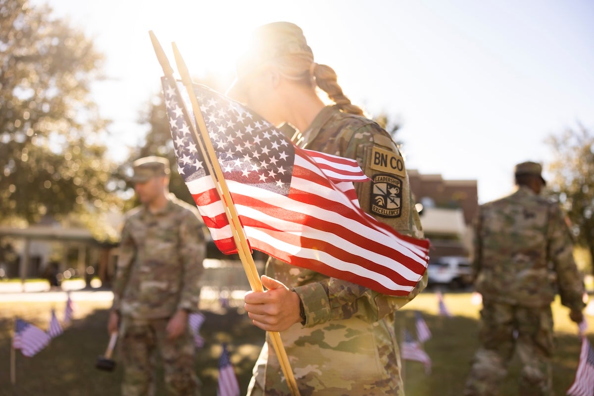 student-veterans holding American flags while in uniform