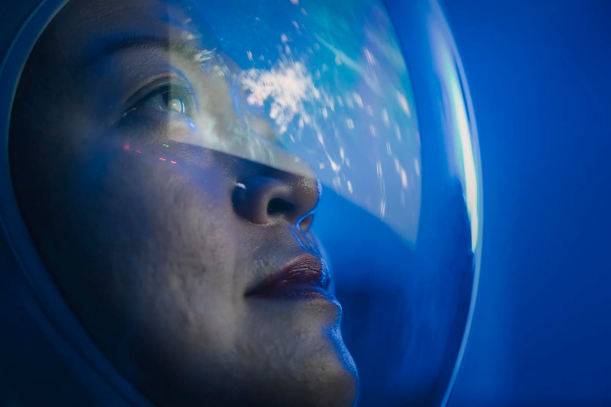 Astronaut looking at earth through window from spaceship at outer space