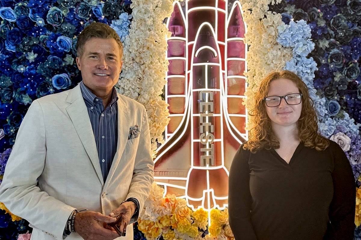 Mark Norato and Faith Kidwell standing in front of a lit up space shuttle sign