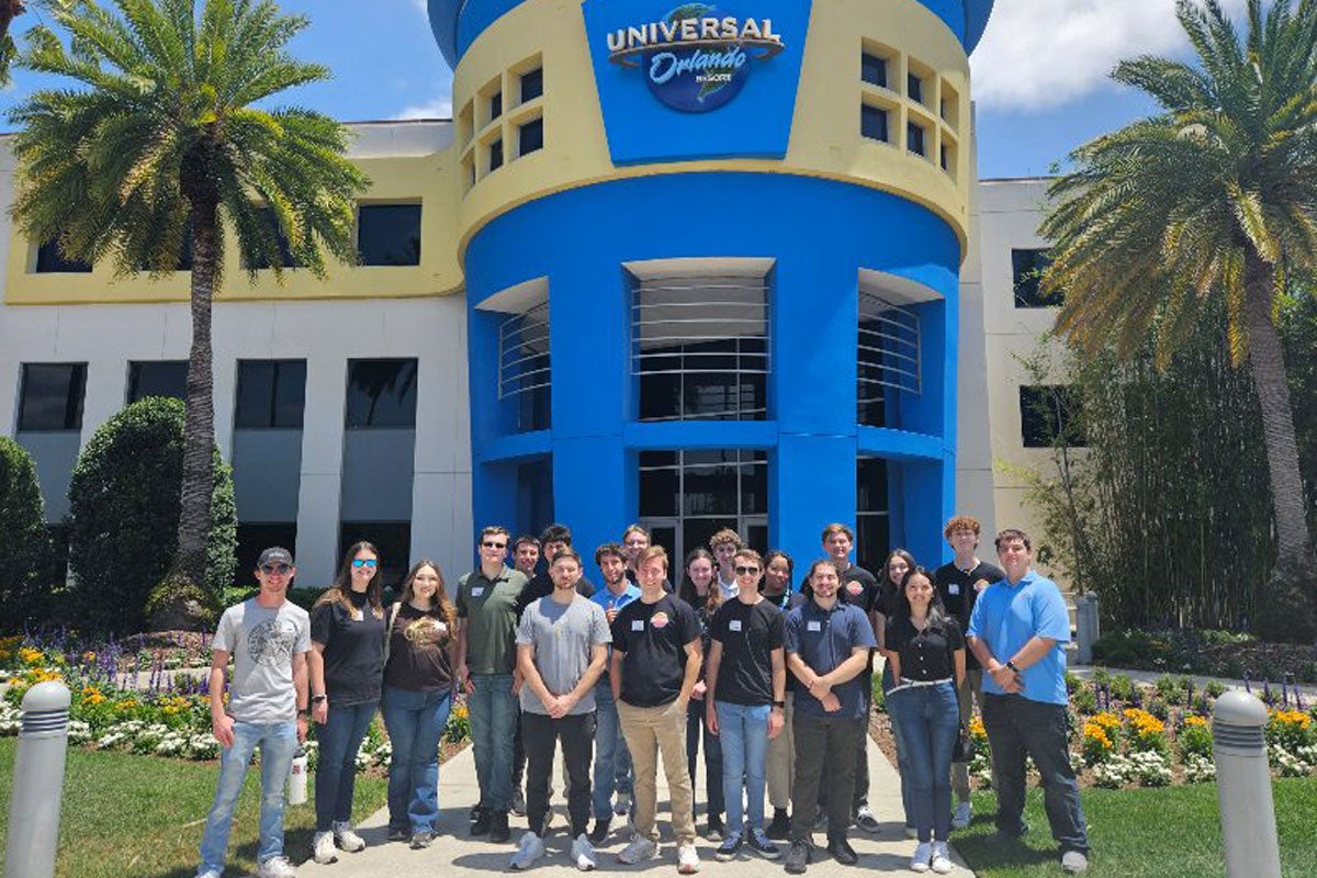 A group of students standing in front of a Universal Orlando resort building