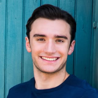 Portrait of UCF computer science student Luke Dederich smiling in front of a teal wooden background.