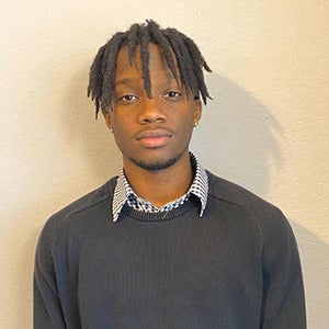 UCF finance major Cameron Alexis poses in front of a plain beige wall.