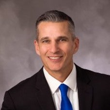 Person standing behind gray background.