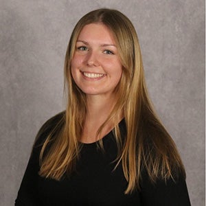 UCF aerospace engineering student Mallorie Simpson poses in front of a light grey studio backdrop.