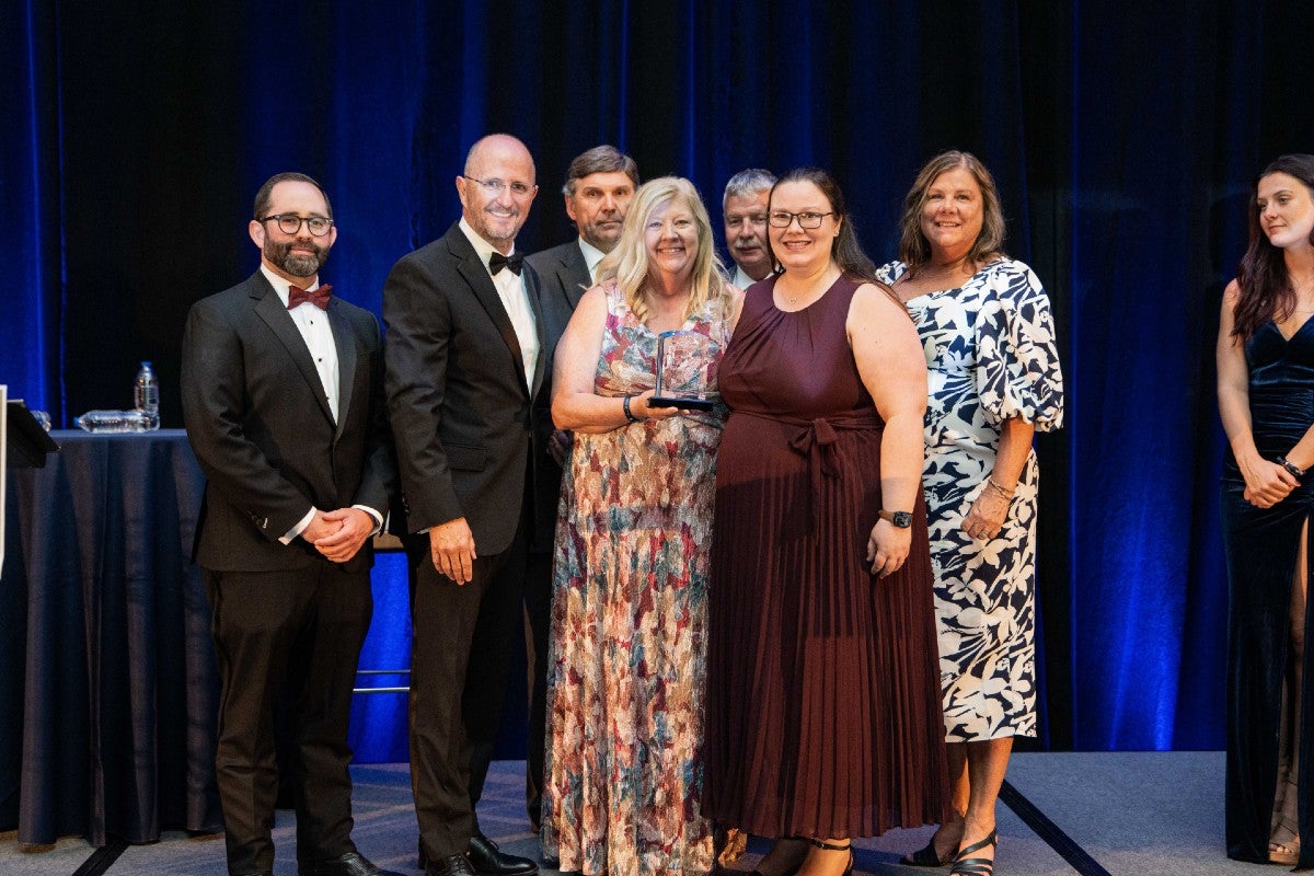 Kathryn Valentine standing onstage holding the Miles Anderson Award next to gala presenters and the family members of Miles Anderson.