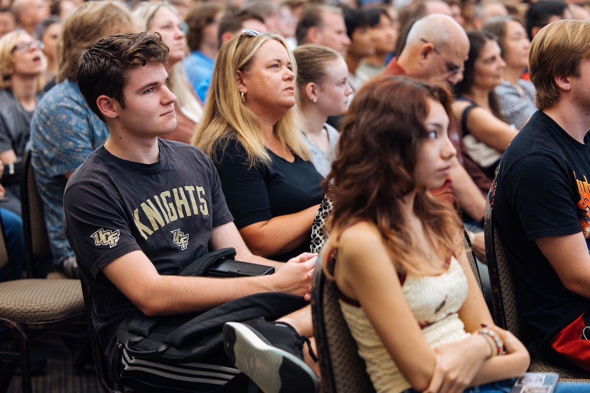 A group of UCF students and their families listens to a presentation during summer orientation.