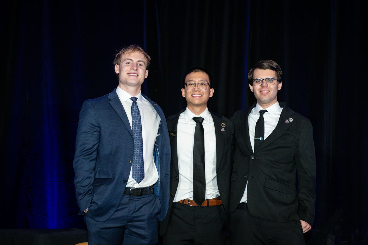 three students wearing suits and ties