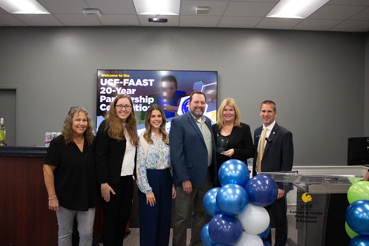 Group of six men and women stand near balloons