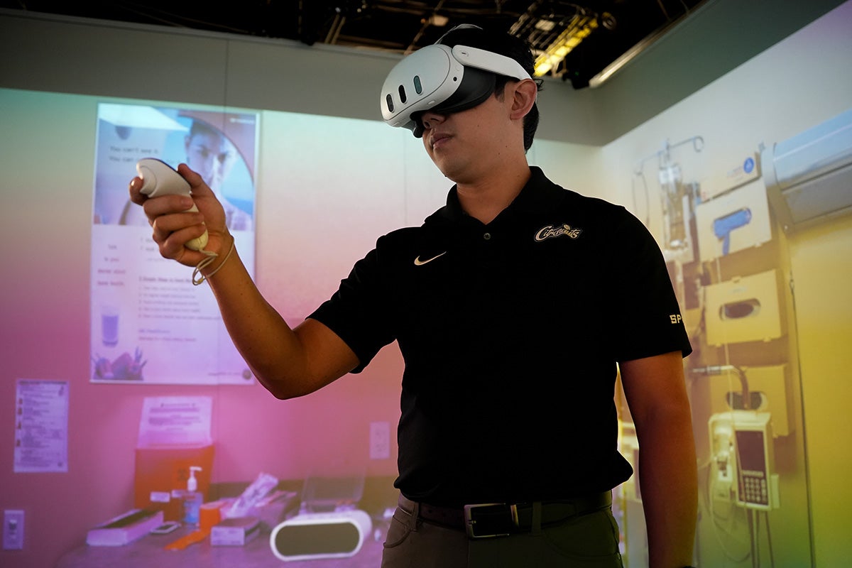 A UCF student wearing a white virtual reality headset holds a controller in one hand.