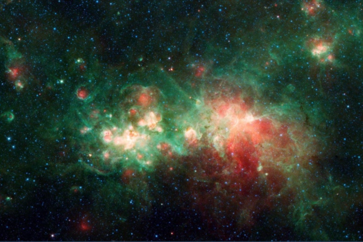 Telescope image of the star-forming nebula W51 in the Milky Way galaxy, displaying vibrant red and green hues.