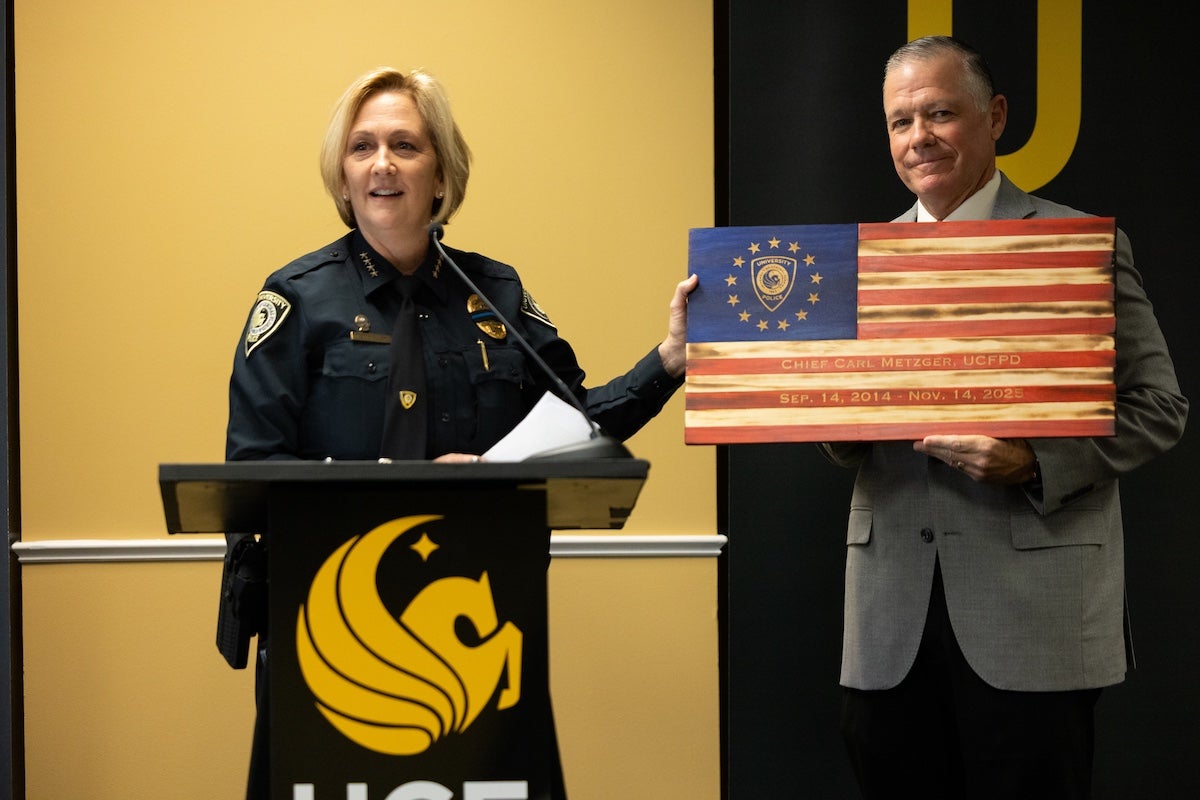 UCF Chief of Police Robin Griffin-Kitzerow presents Carl Metzger with a commemorative gift at his retirement celebration.