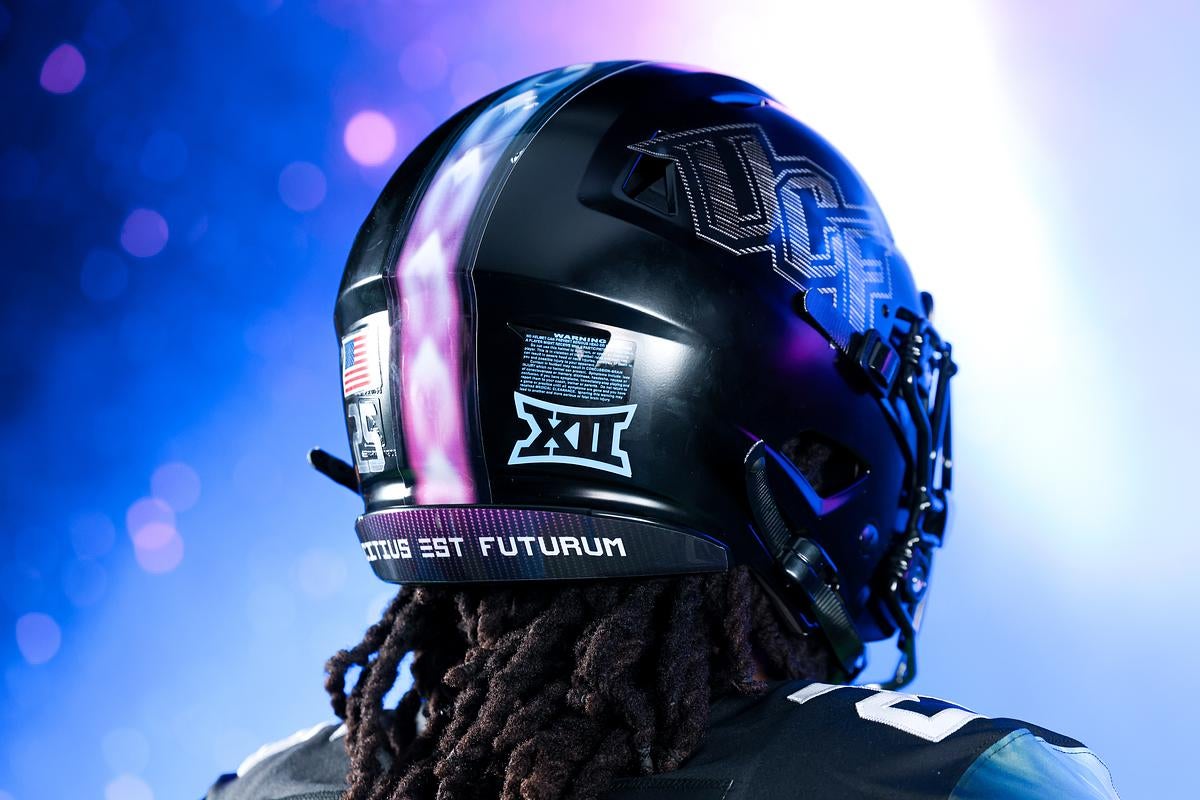 UCF football helmet with space-themed stripe, Big 12 logo, and Latin motto against purple-blue light.