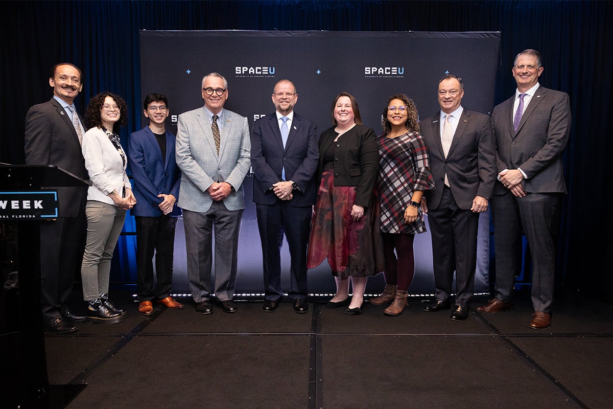 A group of people posing for a photo in front of a SpaceU backdrop