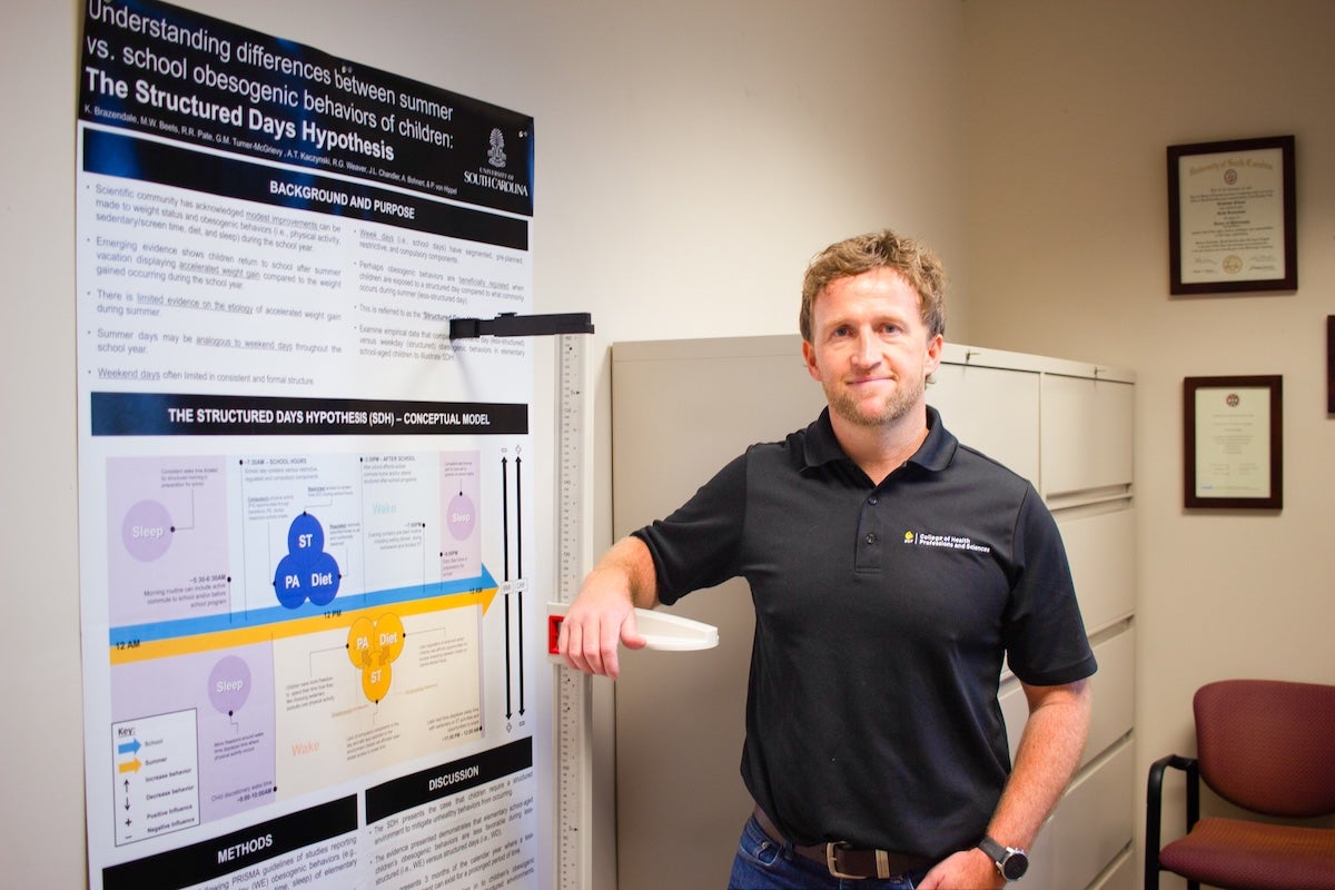 Keith Brazendale standing next to a research poster
