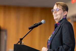 UCF Professor of English Anastasia Salter speaks at a podium into a microphone during the 2026 Faculty Authors’ Celebration.