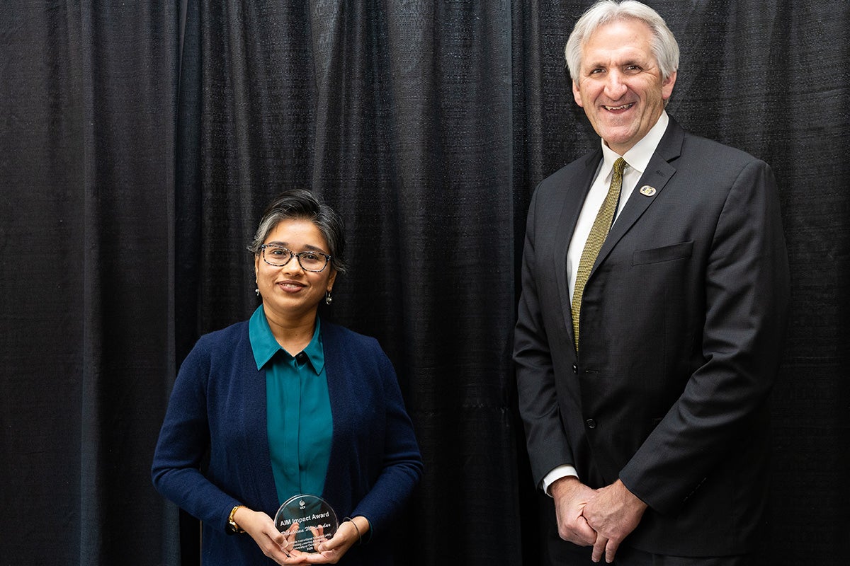 UCF Assistant Professor Debaleena Majumdar and Provost John Buckwalter stand side by side in front of a black backdrop.