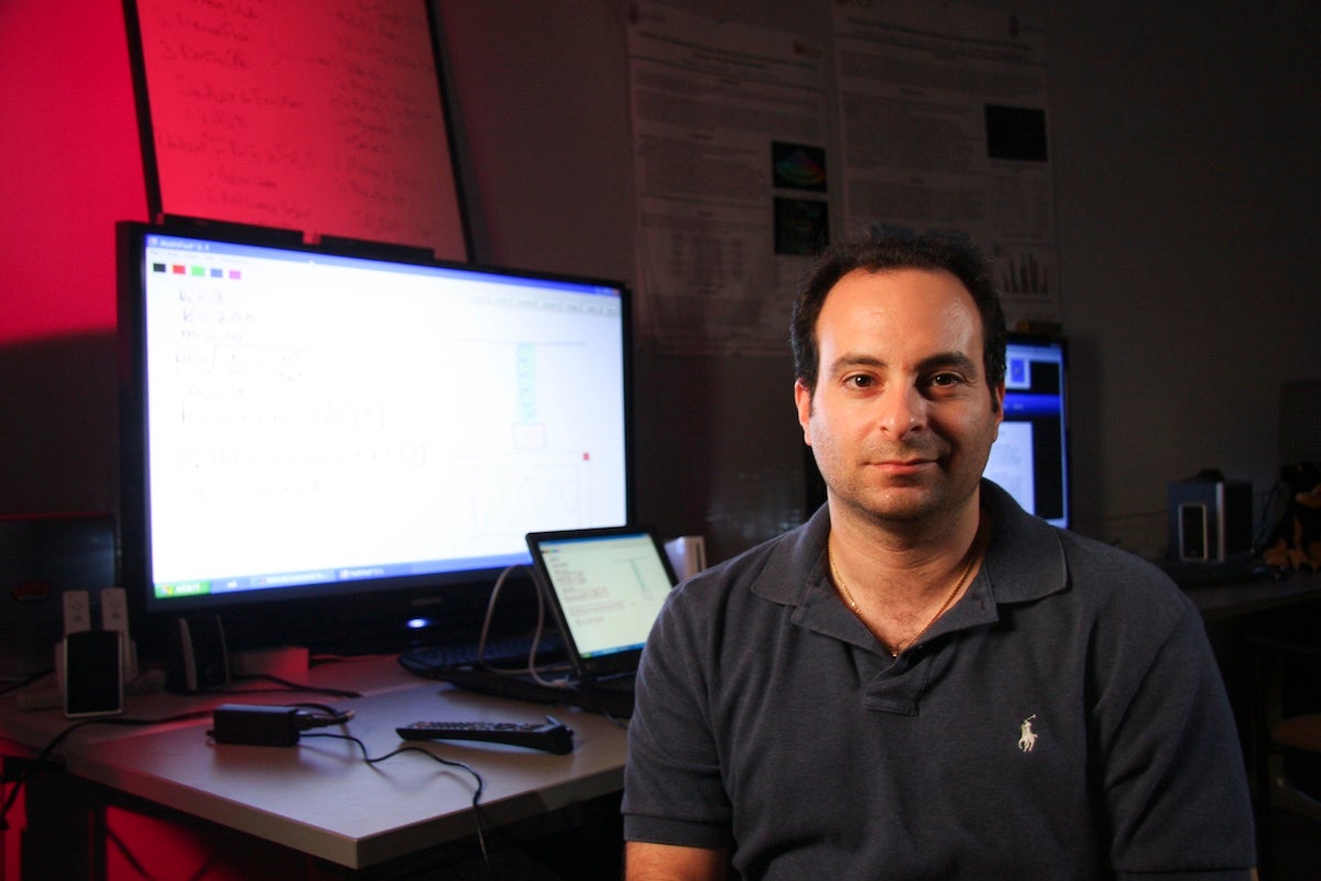 UCF Professor Joseph LaViola Jr. sits next to an illuminated computer screen.
