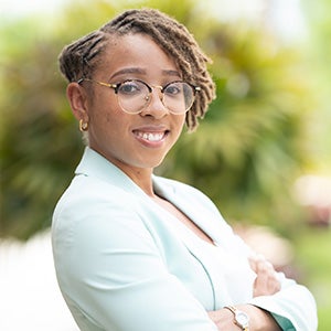 Portrait of Black woman with short hair, glasses and business coat with her arms crossed