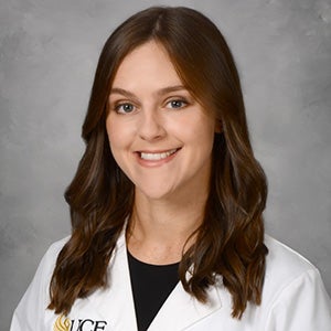 Portrait of brunette woman in white UCF lab coat