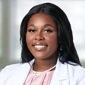 Portrait of smiling woman with straight black hair, in white blazer with pink blouse