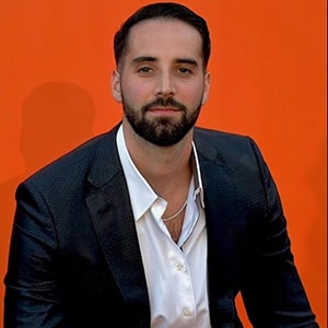 Portrait of bearded man in business suit in front of red backdrop