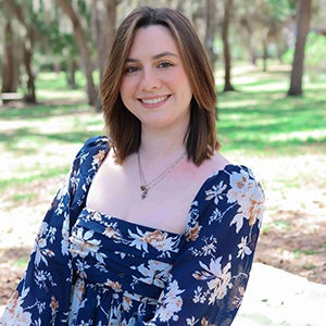 Portrait of smiling woman in floral blue blouse, standing outside